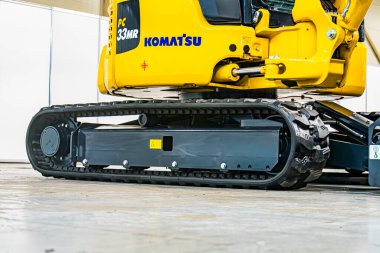 Sarı bir Komatsu 'nun kapalı görüntüsü kazıcıyı izledi, KOMATSU' ya vücutta görünür bir metin, genişletilmiş izler, beton zemin, parlak ışıklandırma, yumuşak gölgeler Kyiv, Ukrayna - 14 Ekim 2025