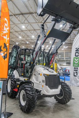 Sanayi tipi beyaz, turuncu aksanlı, NXG marka, kazıcı ve traktörlü bir depo, Avrupa belediye taşımacılığı sergisi Orange bann Kyiv, Ukrayna - 14 Ekim 2025