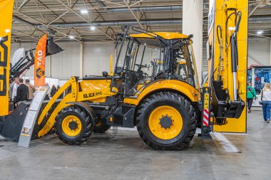 Sarı tırtıl traktörünün yer aldığı sanayi sergi salonu yükleyici eklentisi, cam bölmelerden görülebilen ek sergiler Kyiv, Ukrayna - 14 Ekim 2025