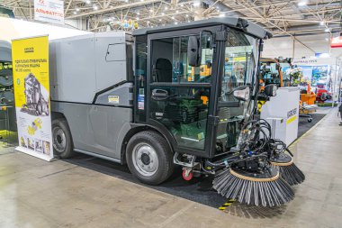 Sarı ve siyah bir yol temizleme makinesinin yer aldığı sanayi teşhir kabini, dönen fırçalar ve görünür drenaj zeminiyle, parlak iç aydınlatma altında, Yellow Kyiv, Ukrayna - 14 Ekim 2025
