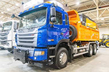 Büyük endüstriyel kamyonlar için kapalı depo veya bakım alanı. Turuncu konteynır eklentisi olan mavi kamyon, merkezi olarak park edilmiş, hatta ışıklandırma, beton Kyiv, Ukrayna - 14 Ekim 2025