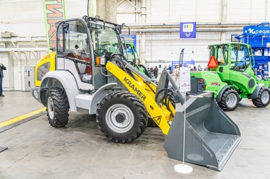 Büyük çoğunluğu sarı ve gri olmak üzere iki motor grevcisinin sergilendiği kapalı sergi, büyük siyah tekerlekler ve markalaştırma ekipmanlarıyla, muhtemelen Kyiv, Ukrayna - 14 Ekim 2025