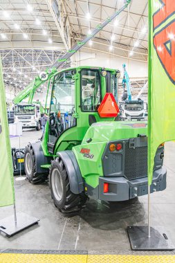 Kapalı alanda endüstriyel ortam, John Deere kepçe yükleyici yeşil, turuncu yansıtıcı üçgen, ahşap yüzey üzerinde JOHN derin isim plakası olası vinç veya li Kyiv, Ukrayna - 14 Ekim 2025