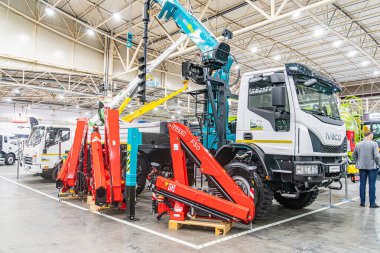 Endüstriyel atölye veya depo sahnesi Eklemli kolları, sarı taksisi ve koruyucu personeli olan merkezi kırmızı vinç kamyonu Kyiv, Ukrayna 'da 14 Ekim 2025