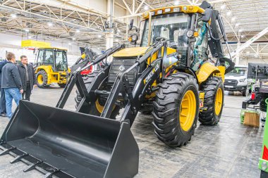 Büyük sarı buldozer ve küçük inşaat makinelerinin yer aldığı kapalı sanayi sergisi, mekanik atlet Kyiv, Ukrayna 'daki insanlarla çelişiyor - 14 Ekim 2025