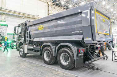 Gri eklemli taşıyıcı kamyon, endüstriyel galeride, beton zeminde işaretler, sessiz renk şeması, yapay aydınlatma, kısmen karanlık b Kyiv, Ukrayna - 14 Ekim 2025