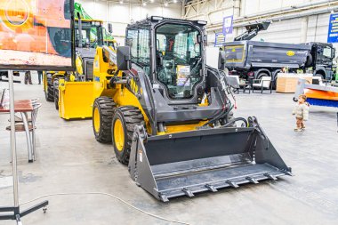 Sarı ve siyah patinaj dümeninin yer aldığı kapalı sanayi sergisi off-road lastikleri, açılı sağ arka plan geniş bir endüstriyel ortam gösteriyor, yüksek c Kyiv, Ukrayna - 14 Ekim 2025