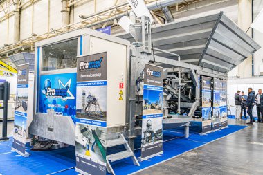 Mavi duvarlara karşı sergilenen büyük, karmaşık bir gıda veya malzeme işleme makinesinin yer aldığı kapalı sergi. Promosyon materyalleri ve panolarında metin ve im Kyiv, Ukrayna - 14 Ekim 2025