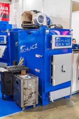 Beton bir zemindeki mavi endüstriyel ekipman, muhtemelen bir fabrika veya sergi alanında. Etikette, yapay ışıklandırma illüstrasyonu Kyiv, Ukrayna - 14 Ekim 2025