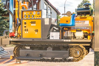 Sarı ve mavi etiketli bir Solota makinesiyle endüstriyel sahne, denetim, göstergeler ve tekerleklerle donatılmış arka planda yeşil ağaçlar, bulutlu gökyüzü, Kyiv, Ukrayna - 14 Ekim 2025