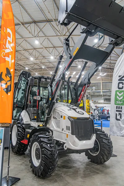 Sanayi tipi beyaz, turuncu aksanlı, NXG marka, kazıcı ve traktörlü bir depo, Avrupa belediye taşımacılığı sergisi Orange bann Kyiv, Ukrayna - 14 Ekim 2025