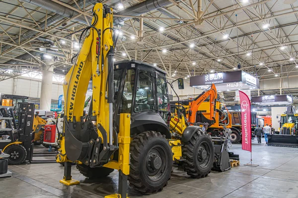 Kapalı alanda buldozerler, sarı, siyah, turuncu ve siyah makineler de dahil olmak üzere inşaat ekipmanları sergileniyor.