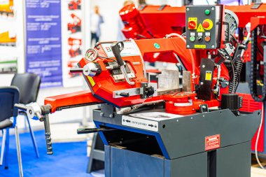 Sanayi ortamında veya sergi kabininde bulunan kırmızı ve gri bir CNC makinesinin yakın plan görüntüsü, metal bileşenler, klempler, kollar ve merkezi silindirik s Kyiv, Ukrayna - 14 Ekim 2025