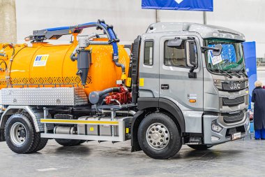 Endüstriyel bir ortamda iki araç, biri konteynır tankı olan turuncu bir kamyon ve diğeri gri bir kamyon, beton bir katta, muhtemelen bir depo Kyiv, Ukrayna - 14 Ekim 2025