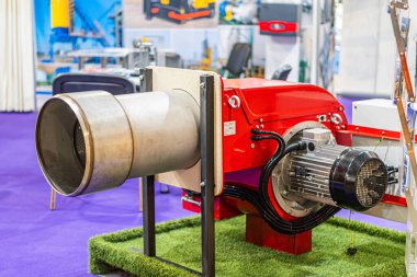 Kırmızı ve gümüş endüstriyel motor, siyah bir standa monte edilmiş, suni çim bazlı bir metal silindir, parlak açıkları olan, yelpaze Kyiv, Ukrayna - 14 Ekim 2025