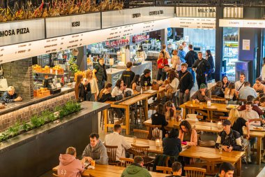 Yüksek tavanlı, endüstriyel aydınlatma, nötr renk paleti grisi, bej, kahverengi, dağınık ahşap masalar, yemek gereksinimleri, Cust Kyiv, Ukrayna - 19 Eylül 2025