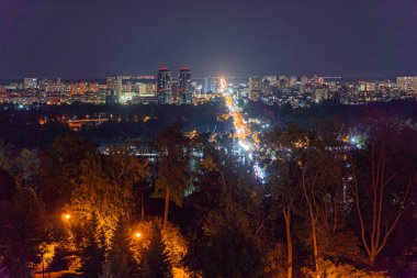 Kyiv 'in gece panoramasında çeşitli yüksek binalar, aydınlık sokaklar ve zıt sonbahar yapraklarının yer aldığı iyi ışıklandırılmış şehir manzarası Kyiv, Ukrayna - 19 Eylül 2025