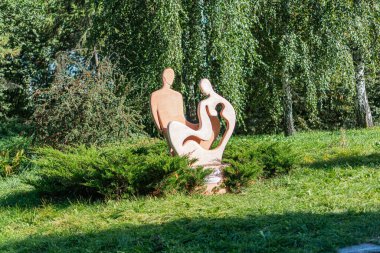 Bir bahçede ya da park ortamında iki çıplak heykel, muhtemelen canlı benzeri özelliklerle etkileşimde, heykellerin yumuşak kıvrımları ve gerçekçi detayları var, ince zeka ile uyumlu Kyiv, Ukrayna - 20 Eylül 2025