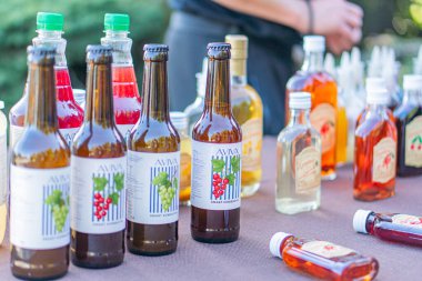 Panayırda gündelik bir masa gösterisi, çeşitli alkollü içecekler sergileniyor. Doğal, yumuşak ışıklandırma sıcak bir atmosfer ve ince gölgeler yaratır. Kyiv, Ukrayna - 20 Eylül 2025