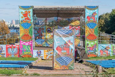 Canlı sahne halıları, hayvan ve mitolojik tasarımları, zengin renkler, yapı iskelesi, mavi sandalyeler, gündüz aydınlatması, olası kültürel referans Kyiv, Ukrayna - 20 Eylül 2025