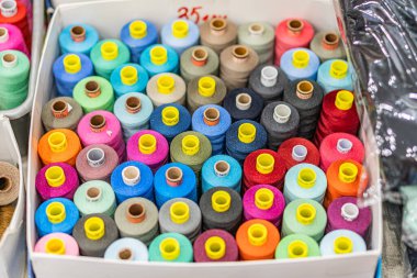 Renkli makaraların koleksiyonu bir panayırda karton bir kutuda sergileniyor, renkli ve bastırılmış renkler değişken olarak Kyiv, Ukrayna - 25 Eylül 2025