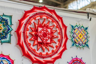 Ukrayna 'dan gelen geometrik halk sanatının kapalı alanda sergilenmesi, soyut tarzda parlak yıldız ve güneşlerin sergilenmesi, büyük kırmızı bir yıldız olup, daha küçükleriyle çevrilidir: Kyiv, Ukrayna - 25 Eylül 2025