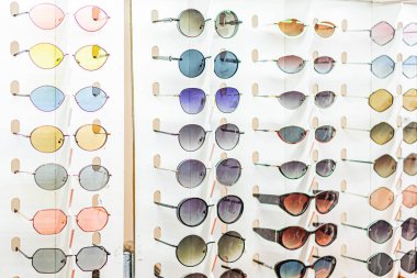 Renkli güneş gözlüklerinin Ukrayna 'daki bir panayırda, beyaz ekran birimlerinde çeşitli açılardan asıldığı görüldü. Renkler arasında pembe, mavi, yeşil, kahverengi ve iki renkli tasarımlar Kyiv, Ukrayna - 25 Eylül 2025