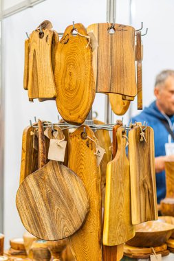 Ukrayna panayırında bir askıda sergilenen dört tahta kesme tahtası, koyu lekeli ahşap desenli ve eşsiz tahıl desenli bir tahtanın karmaşık bir yaprak sınırı var, Wh Kyiv, Ukrayna - 25 Eylül 2025