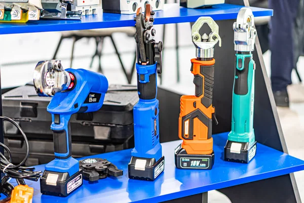 Mavi tezgahlı endüstriyel çalışma alanı, çeşitli elektrikli aletler matkaplar, anahtarlar, pil paketleyiciler, çeşitli renkler siyah, gri, turuncu, yumuşak ortam aydınlatma Kyiv, Ukrayna - 14 Ekim 2025