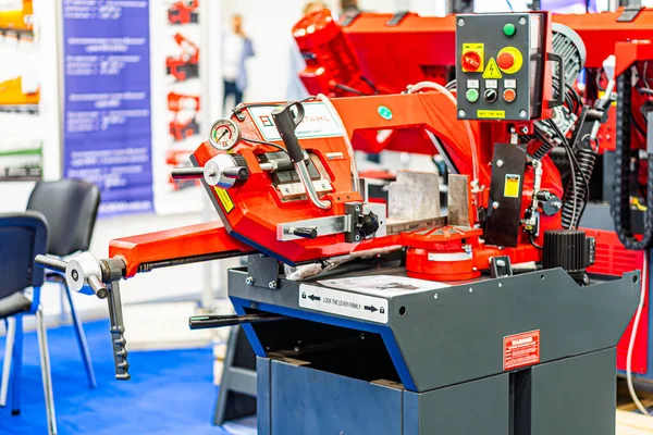 Sanayi ortamında veya sergi kabininde bulunan kırmızı ve gri bir CNC makinesinin yakın plan görüntüsü, metal bileşenler, klempler, kollar ve merkezi silindirik s Kyiv, Ukrayna - 14 Ekim 2025