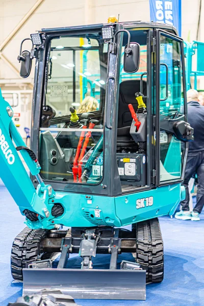 Kapalı alanda kırmızı hidrolik çizgileri olan siyah ve sarı bir tırtıl buldozerinin sergilendiği endüstriyel sergi büyük raylarla donatılmıştır, Kyiv, Ukrayna - 14 Ekim 2025