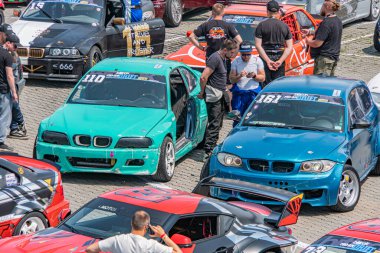 Açık hava araba fuarı ya da etkinliğinde üç farklı araba - mavi, deniz mavisi ve kırmızı bir araç - günlük giysiler içinde hareket eden insanlar, gündüz vakti li Kyiv, Ukrayna 06-15-2025