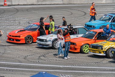 Kyiv 'de bir grup renkli yarış arabası pistte çeşitli giysiler içinde sürüklenen insanlar için hazırlanıyor. Gündüz Kyiv, Ukrayna 06-15-2025 yarışları için hazırlanıyorlar.