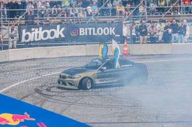 Kyiv Araba Sürükleme Festivali 'nde siyah ve mavi BMW sürüklenen araba, somut bir pistte aerodinamik modifikasyonlar, duman bulutu, yüksek perspektif, bulanık sp Kyiv, Ukrayna 06-15-2025