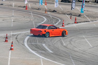 Kyiv Araba Sürükleme Festivali 'nde beton pistte turuncu BMW yarış arabası, arka planda mavi güvenlik bariyerleri ve hafif ışıklandırma Kyiv, Ukrayna 06-15-2025