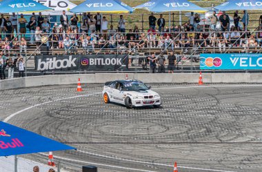 Kyiv Araba Sürükleme Festivali 'nde mavi ve turuncu çizgili beyaz bir BMW' nin yer aldığı dinamik sürüklenme sahnesi Ukrayna, Kyiv, 06-15-2025