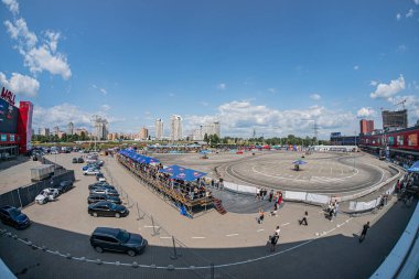 Kyiv Araba Sürükleme Festivali 'nde gün ortasında bir şehir caddesinde bir döner kavşak, binalar, yayalar, trafik, yüksek yapılar ve kentsel unsurlar Kyiv, Ukrayna 06-15-2025