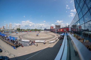 Kyiv 'de bir BMW arabası ve sürüklenen bir rekabetin yer aldığı açık hava etkinliği kırmızı yarış pisti, zıt çadırlar ve modern kentsel yapı Kyiv, Ukrayna 06-15-2025