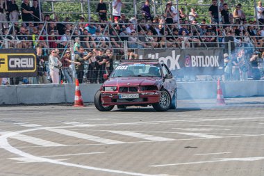 Kırmızı BMW arabası Kyiv Araba Sürükleme Festivali 'nde aerodinamik paneller, dönen arka lastikler ve dumanlı kalabalık Kyiv, Ukrayna 06-15-2025