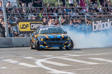 Mavi ve sarı BMW araba Kyiv Araba Sürükleme Festivali sırasında hareket halinde, gündüz saatlerinde bir yarış pistinin tozunu attırıyor, açık hava koşulları Cl Kyiv, Ukrayna 06-15-2025