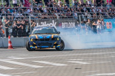 Mavi BMW arabası Kyiv Araba Sürükleme Festivali 'nde, etrafı dumanla çevrili, Ukrayna, Kyiv, Ukrayna 06-15-2025' ten izleyiciler tarafından izleniyor.