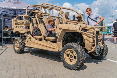 İnsanların kamuflaj yeşil ATV ya da devriye arabası ile etkileşime geçtiği sahne, soldaki çocuk, sağdaki kişi, arka plandaki ek figürler, dış mekan, gün ışığı, Kyiv, Ukrayna 06-15-2025
