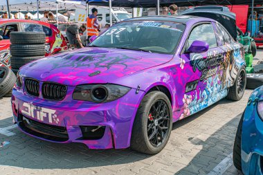 Kyiv Araba Sürükleme Festivali 'nde modifiye edilmiş BMW arabası, siyah aksanlı çarpıcı bir mor ve pembe renk şeması sergiliyor, büyük arka kanat spoiler, yan etekler, aerodyna Kyiv, Ukrayna 06-15-2025