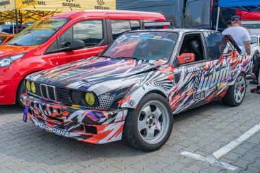 Yan yana park edilmiş arabalar Kyiv Araba Sürükleme Festivali Kırmızı araba Sarı, beyaz aksanlı ve parlak bitiş, büyük siyah jantlar mor, gri tasarım, promine Kyiv, Ukrayna 06-15-2025