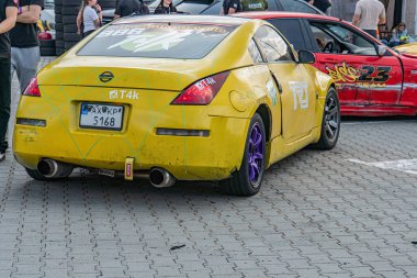 Üç spor araba kaldırım taşlı bir sokağa park edilmiş, gündüz vakti, doğal ışık, sarı Nissan GT-R GTR1, beyaz çizgili kırmızı spor araba, arka plan sarı araba bl Kyiv, Ukrayna 06-15-2025