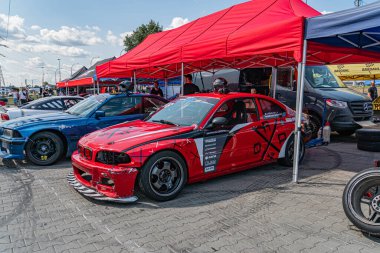 Kırmızı BMW yarış arabası bir araba fuarında ya da yarış etkinliğinde hasar gördü, arka planda kırmızı çatılı bir çadırın altında Kyiv, Ukrayna 06-15-2025