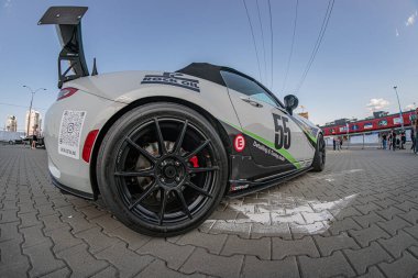 Siyah jantlı ve yeşil çıkartmalı gümüş Mazda yarış arabası, şehir merkezindeki tuğladan yolda kırmızı çıkartma. Görünür 68 numaralı araç, Natur Kyiv, Ukrayna 06-15-2025 tasarımı sergileniyor.