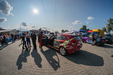 Kyiv Araba Sürükleme Festivali 'nde BMW arabası, tuğladan yapılmış yapılı hareketli bir açık hava etkinliği, odak noktası olarak canlı kırmızı ve sarı araba, çeşitli yaşlardan insanlar ve T Kyiv, Ukrayna 06-15-2025