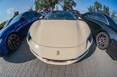 Beyaz bulutlu mavi bir gökyüzünün altında, tuğla kaldırımda sergilenen üç lüks spor araba. Ağaçların en yakını parlak aerodinamik Kyiv, Ukrayna 06-15-2025