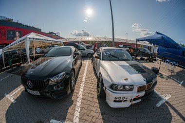 Kyiv 'de 91 numaralı siyah BMW ve beyaz yarış arabasının yer aldığı sokak etkinliği, zıt ayarlar, çadırlı açık hava ortamı, mavi gökyüzü Kyiv, Ukrayna 06-15-2025